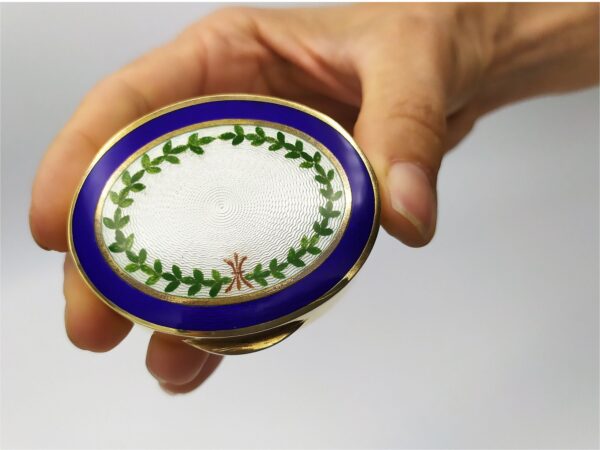 Snuff Box or Pill Box in 925/1000 sterling silver gold plated with translucent fired enamel on guillochè and hand painted miniature of floral wreath. In a human hand.
