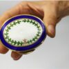 Snuff Box or Pill Box in 925/1000 sterling silver gold plated with translucent fired enamel on guillochè and hand painted miniature of floral wreath. In a human hand.
